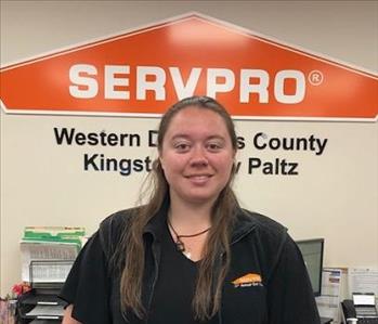 A photo of a smiling female SERVPRO employee with long brown hair in a black SERVPRO shirt