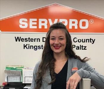 A photo of a smiling female SERVPRO employee with long brown hair in a gray SERVPRO sweater