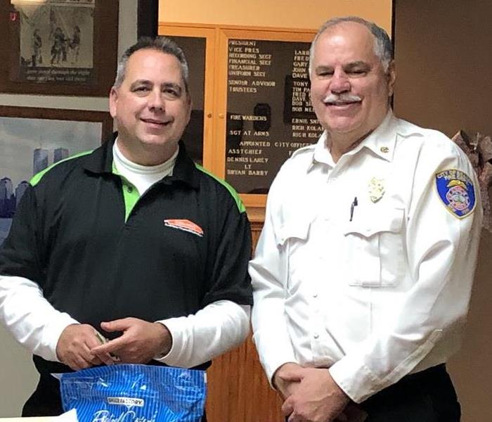 A SERVPRO employee smiling for a photo with the fire department chief 