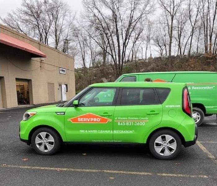 2 green SERVPRO vehicles parked in front of a commercial business