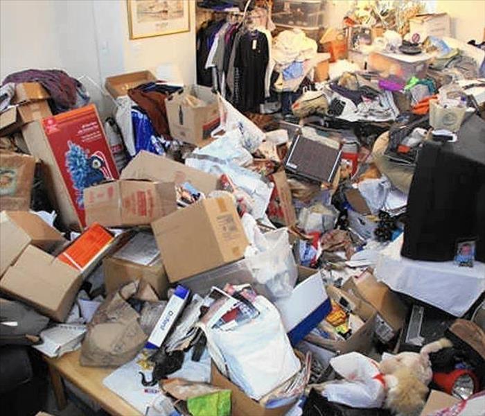 A living and dining room of a home filled with miscellaneous contents displaying a hoarding situation