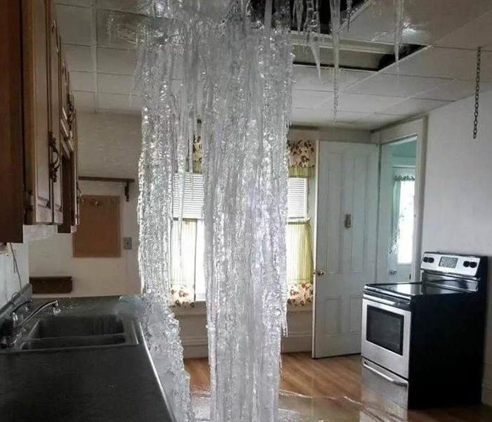 A photo of a frozen waterfall from the ceiling to the floor inside the kitchen of a home