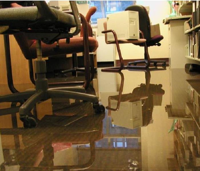 a business office with chairs and desks surrounded by an inch of water on the floor.