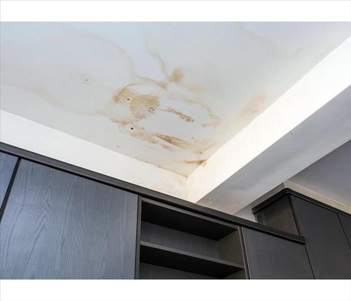 A white ceiling with brown water damage stains spreading 