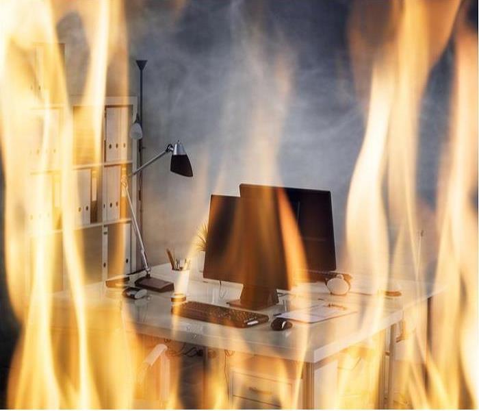 An empty office desk, computer, equipment and files on fire