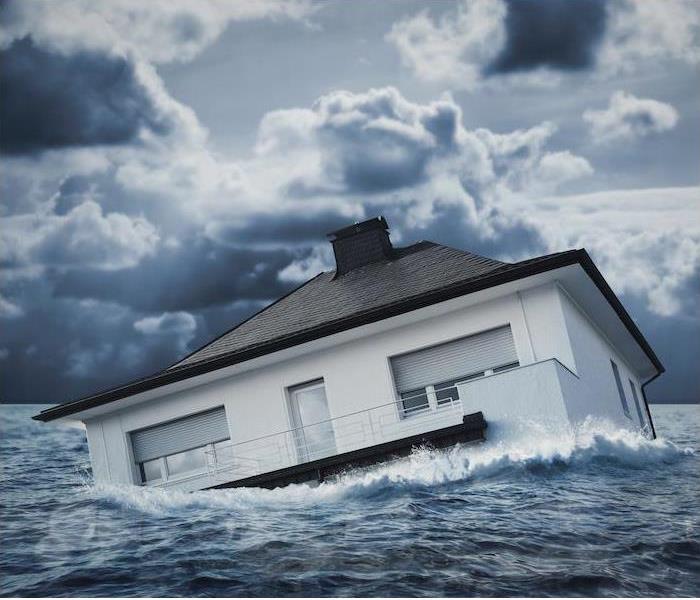An image of a white house floating sideways in the ocean under stormy skies.