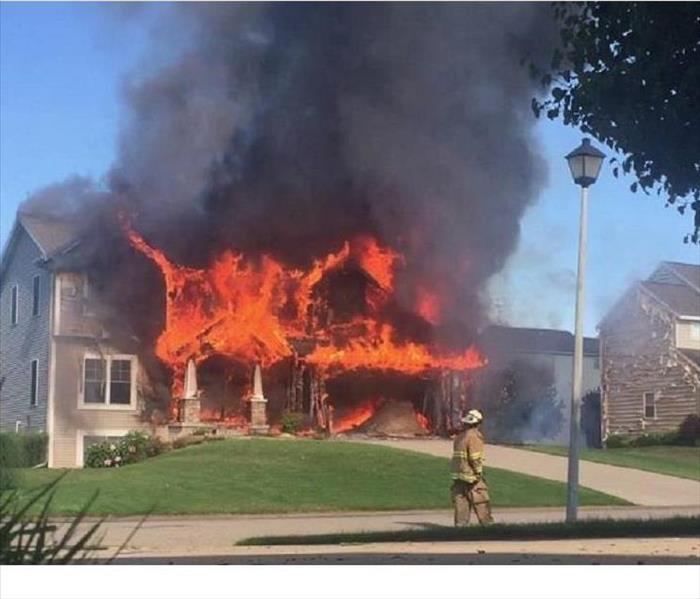 A newly built 2-story home with flames and smoke coming out the front