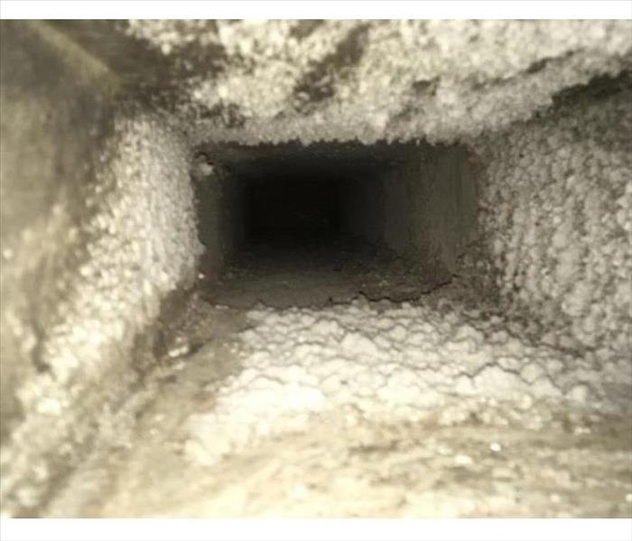 A photo of an interior air duct covered with dust and debris
