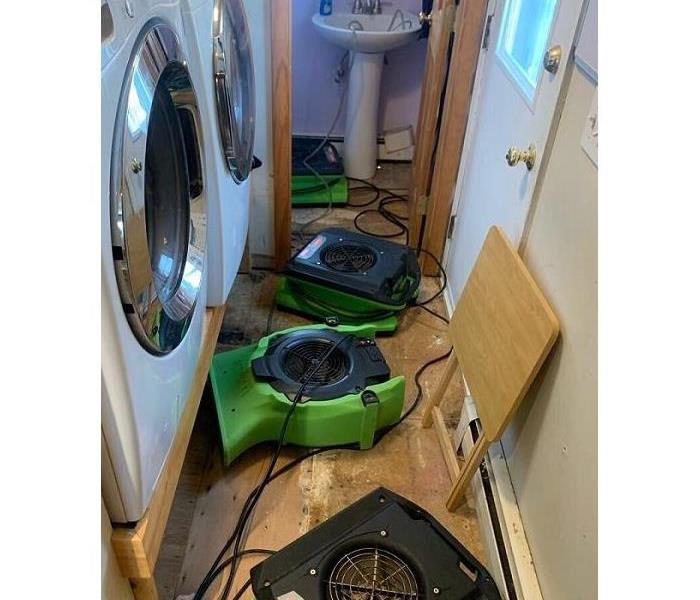 SERVPRO drying machines set up around washing machines inside a home