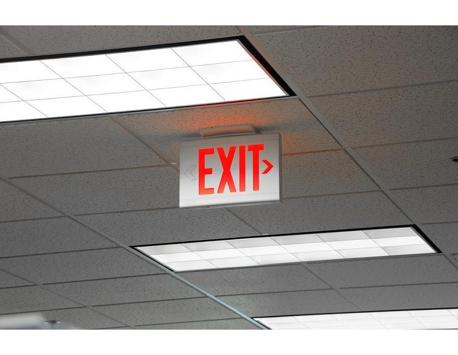A photo of the ceiling of an office with a red Emergency Exit sign hanging from it