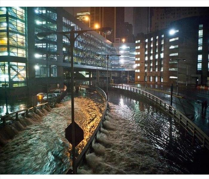 A photo of high rises, freeways and sidewalks flooded at night in a metro city