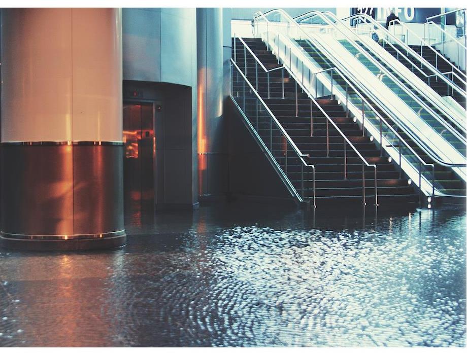 A large staircase in a lobby of a commercial building surrounded by water from flooding