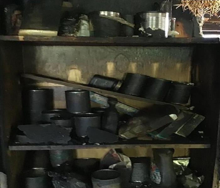 Cans of food covered completely in black soot from a house fire.