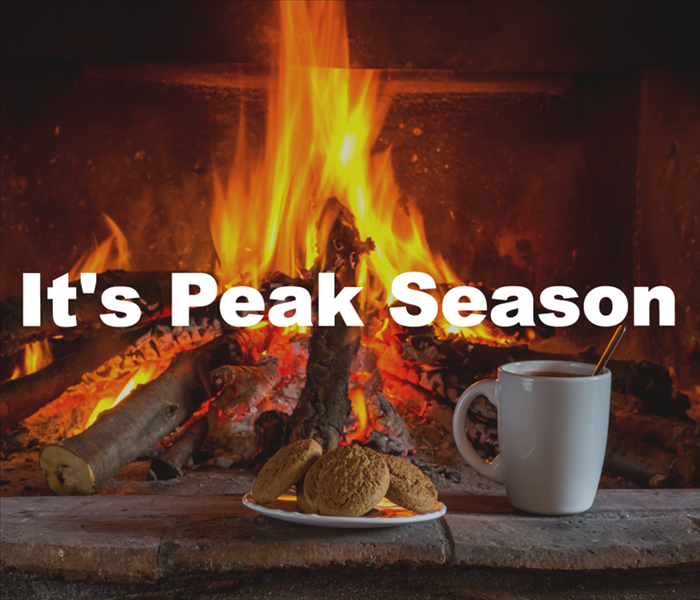 A lit fireplace with a cup of coffee and a plate of cookies placed in front of it with the words "It's Peak Season" displayed