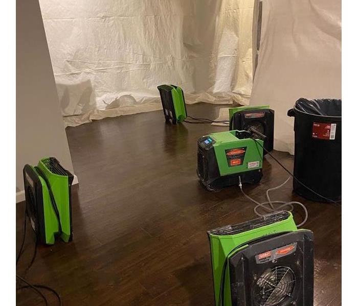 Rooms contained with plastic sheeting, only allowing the hardwood floors and SERVPRO green equipment to be exposed.