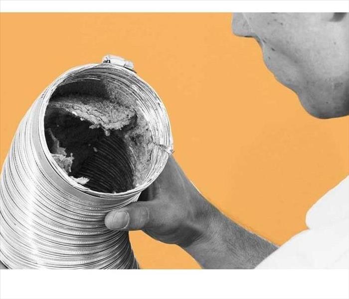 An image of a man looking into a debris-filled dryer vent.