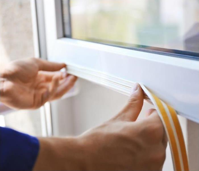 A man installing weather stripping on a white window